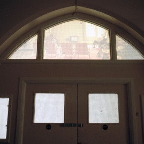 Back projection of empty hospital wards on window above ward doors.